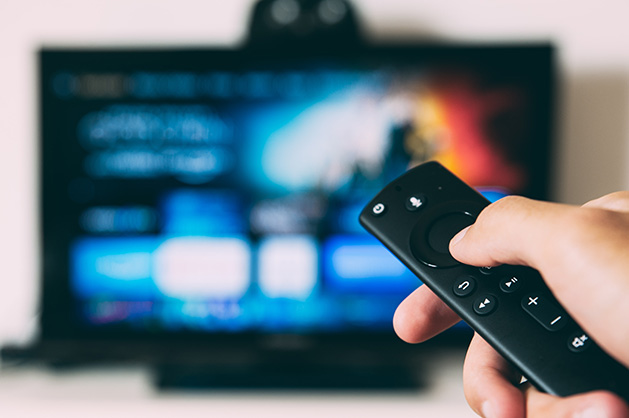 A person holds a remote while watching a streaming service.