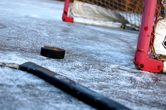 A hockey stick and puck rest in front of the net on an ice rink in Maple Grove.