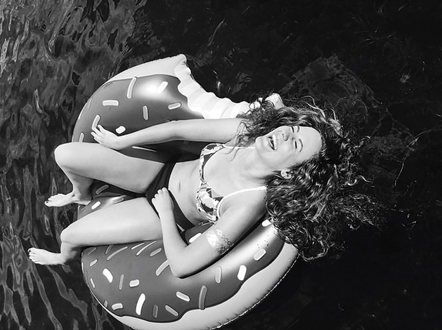 A woman lounges on an inflatable donut in a pool.