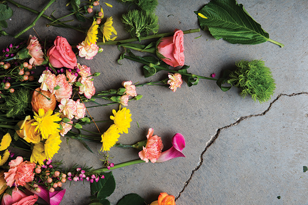 A variety of flowers rest on the concrete.