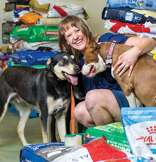 Amy Arellano, founder of pet food nonprofit Feeding Furry Friends, pets two of her dogs.
