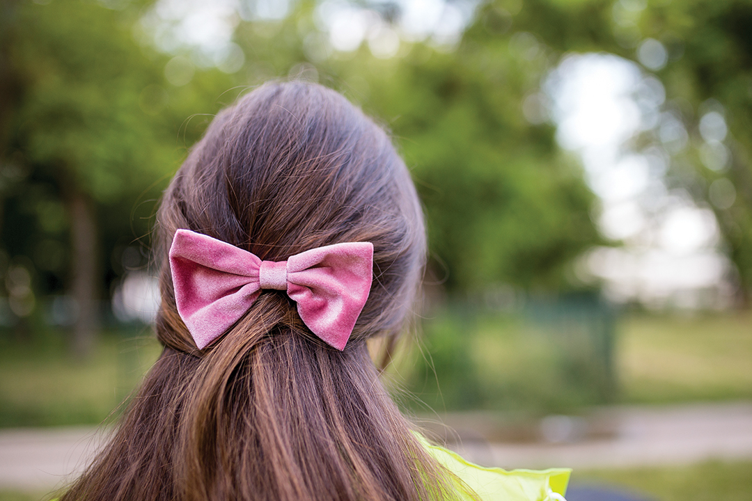 Photo of a beautiful girl with long hair and a bow on her head.