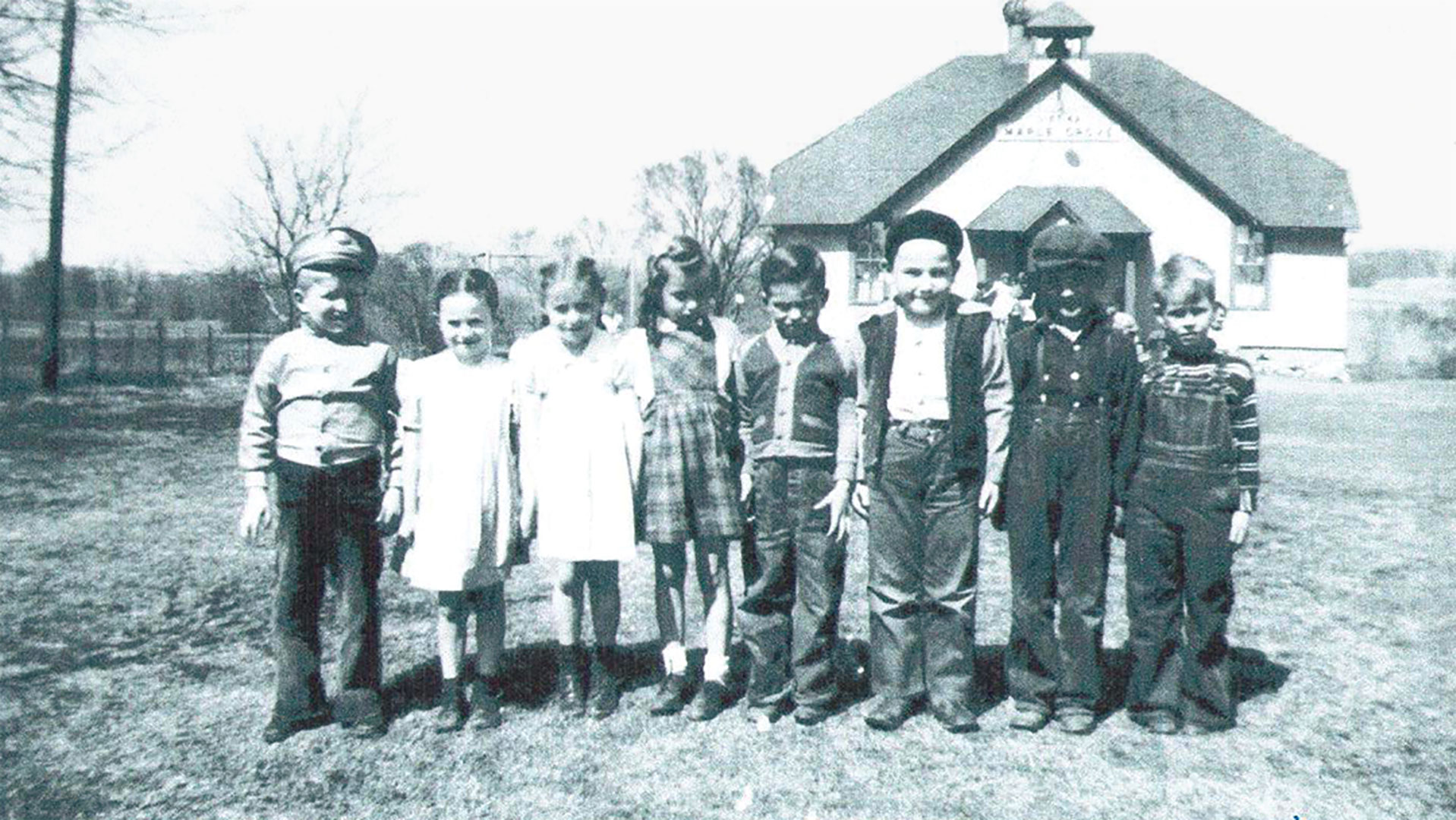 Children proudly pose in front of the Maple Grove School for their first day of school in the 1940s.